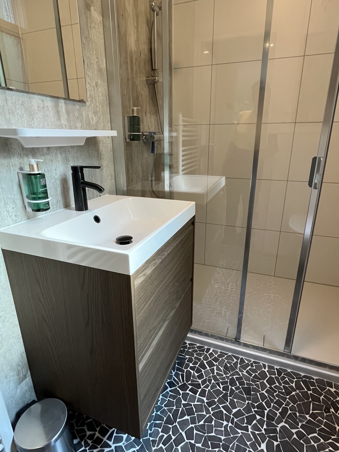 Badkamer met douche, houten wastafelmeubel en Rituals producten