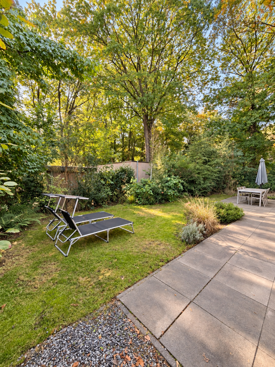 Tuin met ligbedden en terras tussen de bomen